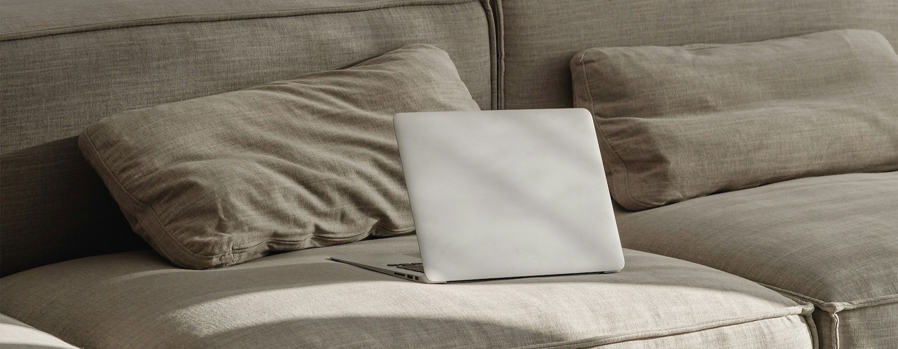 a couch with pillows and a laptop
